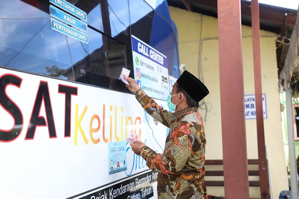 Seorang warga saat menunaikan kewajiban membayar pajak daerah melalui Samsat Keliling
