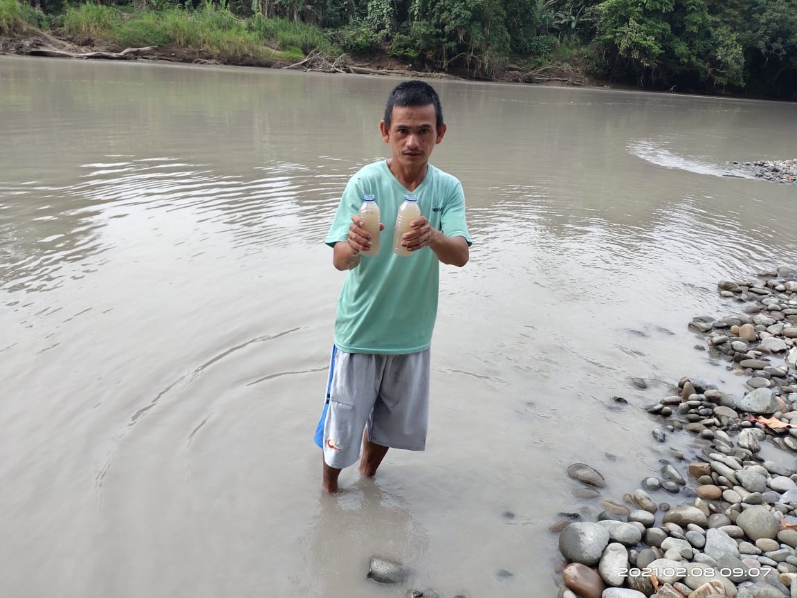 Seorang warga menunjukan air sungai yang tercemar limbah